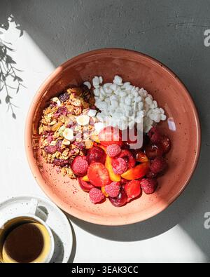 Présentation matinale aux couleurs vives composée d'un bol rempli de fruits et d'un mélange de noix Banque D'Images