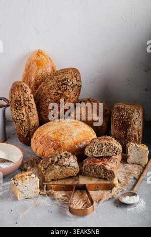 Assortiment de pains artisanaux disposés avec des accessoires rustiques et un fond texturé pour le présentoir Banque D'Images