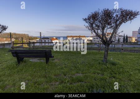 Vue panoramique sur un parc calme à Lisbonne, Portugal, avec un banc en bois, un arbre taillé et de l'herbe verte donnant sur les bâtiments historiques et l'Atlant Banque D'Images