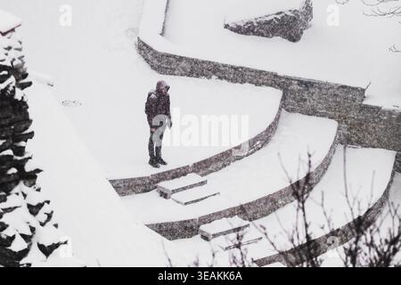 Tallinn, Estonie - 03 janvier 2025 : vue d'une figure solitaire sur des marches de pierre recouvertes de neige, le blanc foncé contrastant avec la silhouette sombre Banque D'Images