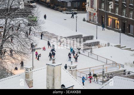 Tallinn, Estonie - 03 janvier 2025 : vue d'une place enneigée vivante avec des figures, encadrée par les toits de bâtiments historiques, où le stam wh Banque D'Images