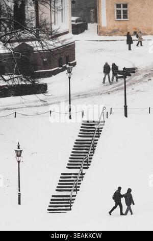 Tallinn, Estonie - 03 janvier 2025 : vue sur les marches enneigées menant à la vieille ville, où les silhouettes des gens traversent le paysage hivernal Banque D'Images