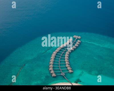 Vue aérienne des bungalows sur l'eau s'étendant dans la mer turquoise, une évasion sereine au paradis, Hoarafushi, Maldives. Banque D'Images