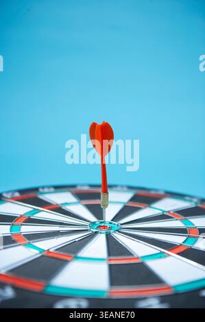 Une seule fléchette est logée au centre d'une cible sur un jeu de fléchettes. Banque D'Images