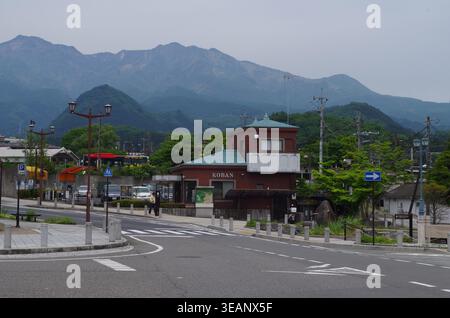 Nikko, Tochigi, Japon - mai 2024 : boîte de police de Koban et bus du patrimoine mondial au centre-ville de Nikko avec chaîne de montagnes en arrière-plan Banque D'Images