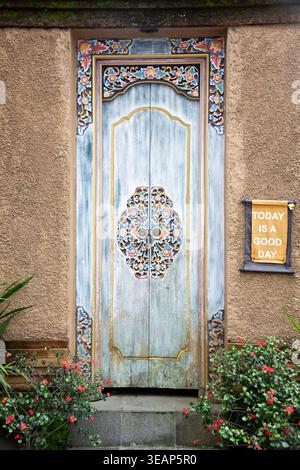 Porte en bois bleu ornée avec des motifs traditionnels complexes sertis dans un mur texturé Banque D'Images