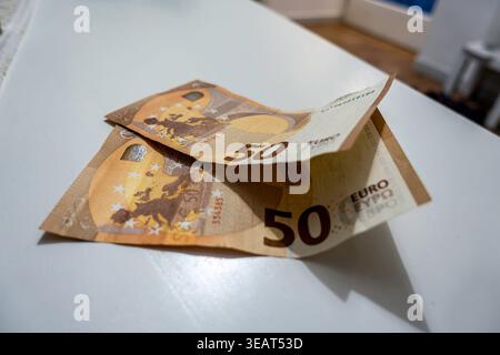 Deux billets de 50 euros reposant sur une surface blanche à Cagliari, Sardaigne. Les notes froissées orange-brun montrent la carte européenne et le symbole monétaire. Banque D'Images