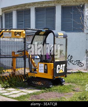 Pomorie, Bulgarie - 23 avril 2026 : Minipelle Caterpillar 301.7D positionnée à proximité d'un chantier de construction avec une zone clôturée et des graffitis visibles sur Banque D'Images