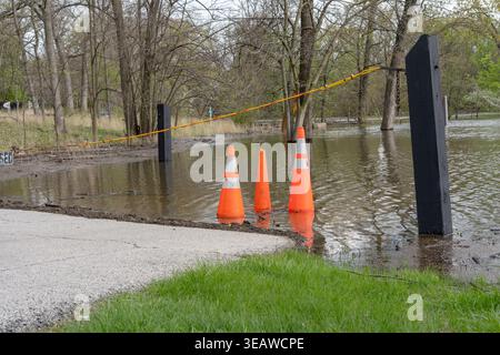 Le sentier du parc a été inondé après de fortes pluies avec des cônes orange et une barrière de marquage d'accès restreint, l'eau couvrant le sol et les arbres dans le backgrou Banque D'Images