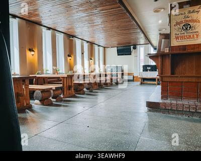 Valmiera, Lettonie - 22 avril 2026 : spacieux intérieur rustique du restaurant avec tables en bois massif, bancs et éclairage chaleureux. Idéal pour hospitalit Banque D'Images