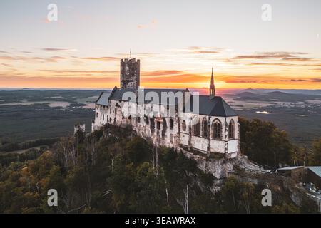 Le château de Bezdez s'élève majestueusement sur une colline, mettant en valeur son architecture médiévale contre un coucher de soleil vibrant. Banque D'Images
