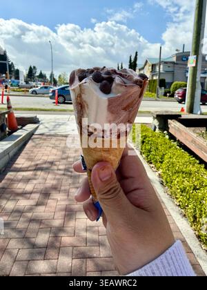 Une personne tenant un cornet de crème glacée enrobé de chocolat Nestlé Drumstick à l'extérieur à Surrey, Colombie-Britannique, Canada, par une journée ensoleillée, le 24 avril 2026. Banque D'Images