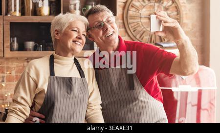 Young couple sur smartphone selfies dans la cuisine Banque D'Images