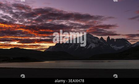 Massif de Torres del Paine avec des sommets enneigés au coucher du soleil, nuages rouges sur Laguna Amarga, Parc National de Torres del Paine, Patagonie, Chili Banque D'Images