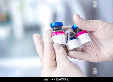 Gros plan d'une main tenant des flacons de vaccin en verre pour injection. COVID 19 Corona virus 2019-ncov. Flacons de vaccin médical avec étiquette blanche vierge Banque D'Images