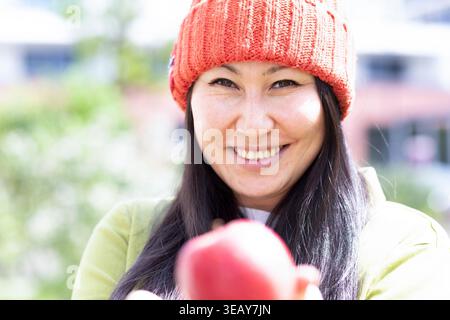 Femme avec un chapeau rouge et une pomme rouge dans les mains Banque D'Images