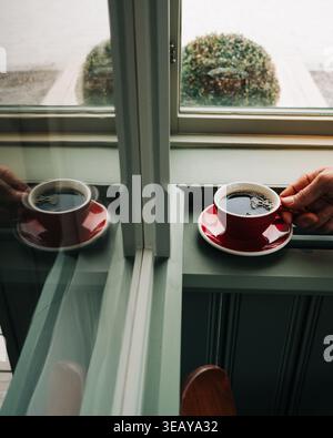 Main tenant un café noir fumant dans un café en Europe Banque D'Images