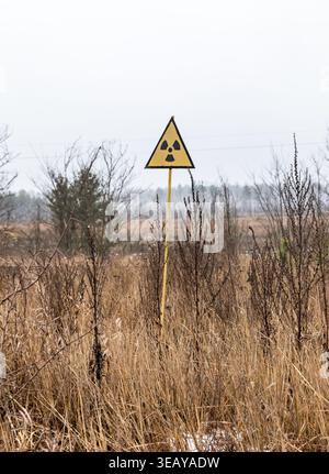 Un panneau d'avertissement de radiation est vu debout dans la zone d'exclusion de Tchernobyl. Le panneau est vu marquant une zone contaminée quarante ans après la catastrophe nucléaire. Banque D'Images
