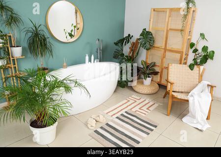 Intérieur de la salle de bains avec plantes vertes, fauteuil et baignoire Banque D'Images