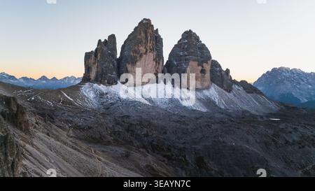 Vue aérienne des majestueux sommets Tre Cime di Lavaredo transperce le ciel, leurs textures robustes contrastant avec la douce lumière de l'aube, Tre Cime di Lavared Banque D'Images