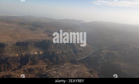 Panorama aérien du désert accidenté canyon et plateau avec chemin de terre sinueux sous ciel brumeux, vaste fond de paysage sauvage. Firmihin Dragon's Blo Banque D'Images