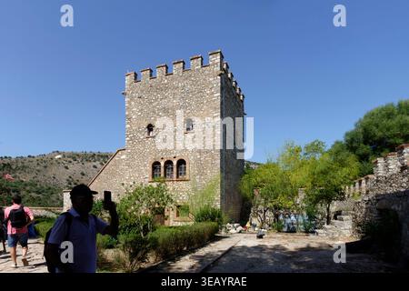 Tour de pierre médiévale et murs de forteresse au parc national de Butrint en Albanie avec des touristes visitant les ruines antiques sous un ciel bleu clair Banque D'Images
