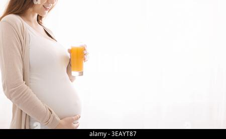 Femme enceinte profitant d'une boisson rafraîchissante dans Soft Light à la maison Banque D'Images