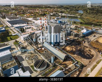 Vue aérienne du complexe industriel avec des structures imposantes et des réservoirs cylindriques au milieu d'une végétation luxuriante, un contraste frappant de l'industrie et de la nature, Cacia, Banque D'Images