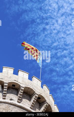 Torres de quart à Valence, une tour médiévale à structure crénelée, drapeau valencien ondulant contre le ciel bleu avec des nuages Banque D'Images