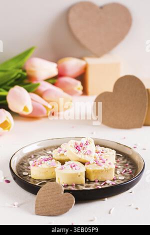 Bonbons au chocolat blanc en forme de coeur avec glaçage sur une plaque vue verticale Banque D'Images