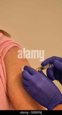 Professionnel de la santé dans des gants bleus injectant seringue dans le bras du patient, concept de soins de santé. Banque D'Images