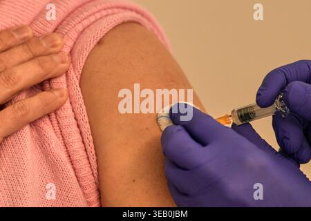 Agent de santé en gants bleus administrant une injection de vaccin dans le bras du patient, gros plan. Banque D'Images