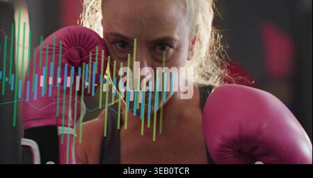 Caleçon face portant un haut de sport sombre tenant des gants roses à la salle de boxe avec superposition de données Banque D'Images