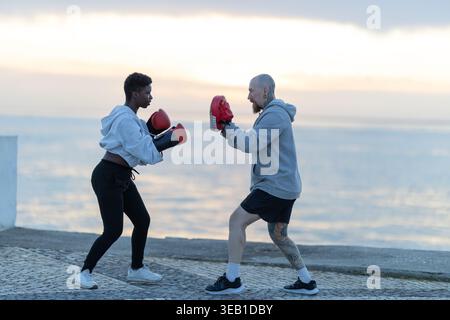 Divers athlètes faisant session d'entraînement de boxe par l'océan Banque D'Images
