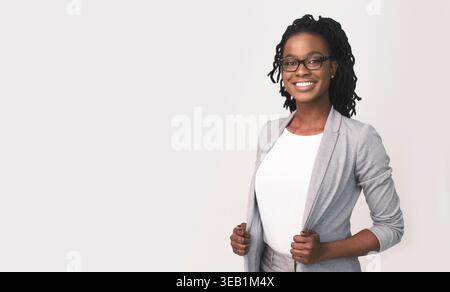 Femme d'affaires confiante posant en tenue professionnelle sur fond neutre Banque D'Images