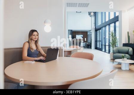 Occupant féminin dans le spacieux salon. Femme appréciant la réunion décontractée dans l'espace lumineux de l'atrium. Individu féminin assis confortablement dans Open communal Banque D'Images