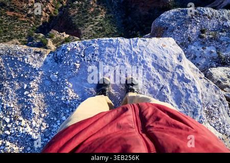 Personne debout sur le bord d'une falaise rocheuse regardant vers le bas Banque D'Images