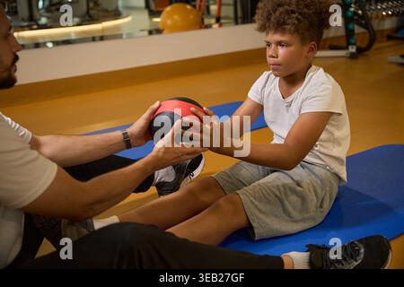 Homme caucasien mentorant un garçon afro-américain au gymnase Banque D'Images