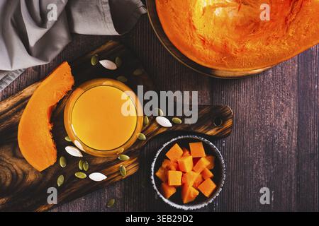 Jus de citrouille frais dans un verre, graines et morceaux de citrouille sur la vue de dessus de table Banque D'Images