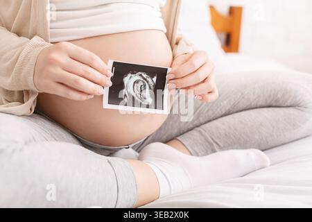 Les parents qui attendent chérissent l'image échographique dans le cadre confortable de la maison pendant la grossesse Banque D'Images