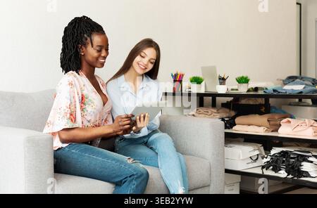 Deux jeunes femmes s'assoient sur un canapé gris dans un espace de travail moderne Banque D'Images