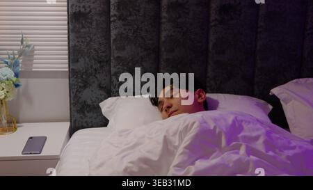 Homme dormant paisiblement dans un lit la nuit Banque D'Images