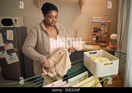 Femme noire séchant la lessive dans le cadre de la maison à faible revenu Banque D'Images