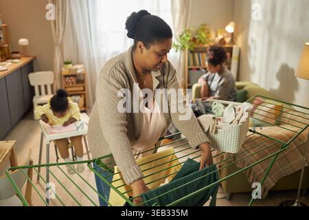 Black Mother sèche la lessive tout en prenant soin des enfants à la maison Banque D'Images