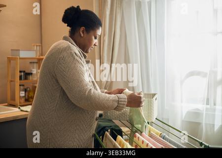 Femme noire séchant la lessive à la maison dans une situation de vie à faible revenu Banque D'Images