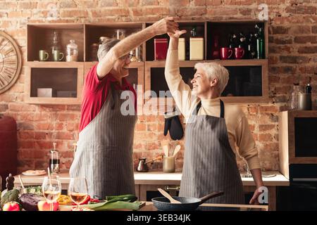 Couple profite d'un moment joyeux tout en cuisinant ensemble dans une cuisine confortable Banque D'Images
