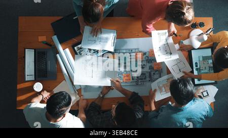 Vue de dessus de l'équipe d'ingénieur civil tenant le plan et debout à la table avec ordinateur portable, plan de projet et plan. Vue aérienne du projet qualifié Banque D'Images