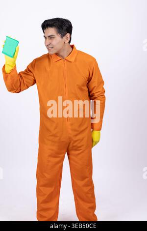Travailleur dans un ensemble orange tenant une éponge de nettoyage Banque D'Images