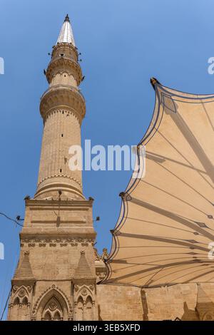 Vue sur le grand minaret en pierre de la mosquée Imam Al-Hussein et une grande verrière architecturale sous un ciel bleu clair au Caire, Egypte. Banque D'Images