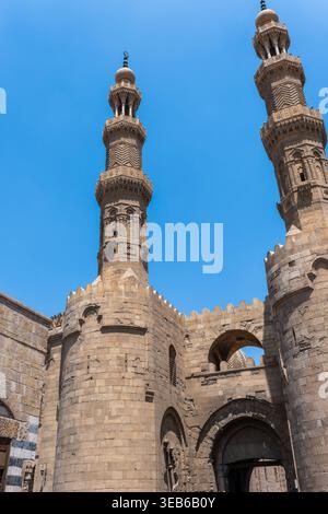 Vue de Bab Zuwayla, la porte médiévale historique avec ses deux imposants minarets ornés et ses murs de pierre massifs sous un ciel bleu clair El-Darb El-Ahmar, Banque D'Images